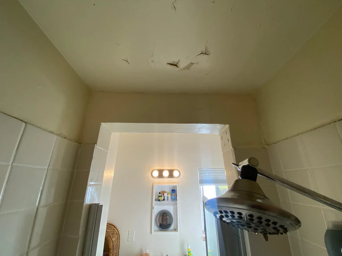 Blistering, peeling paint on a bathroom ceiling above the shower — a common sign of trapped moisture.
