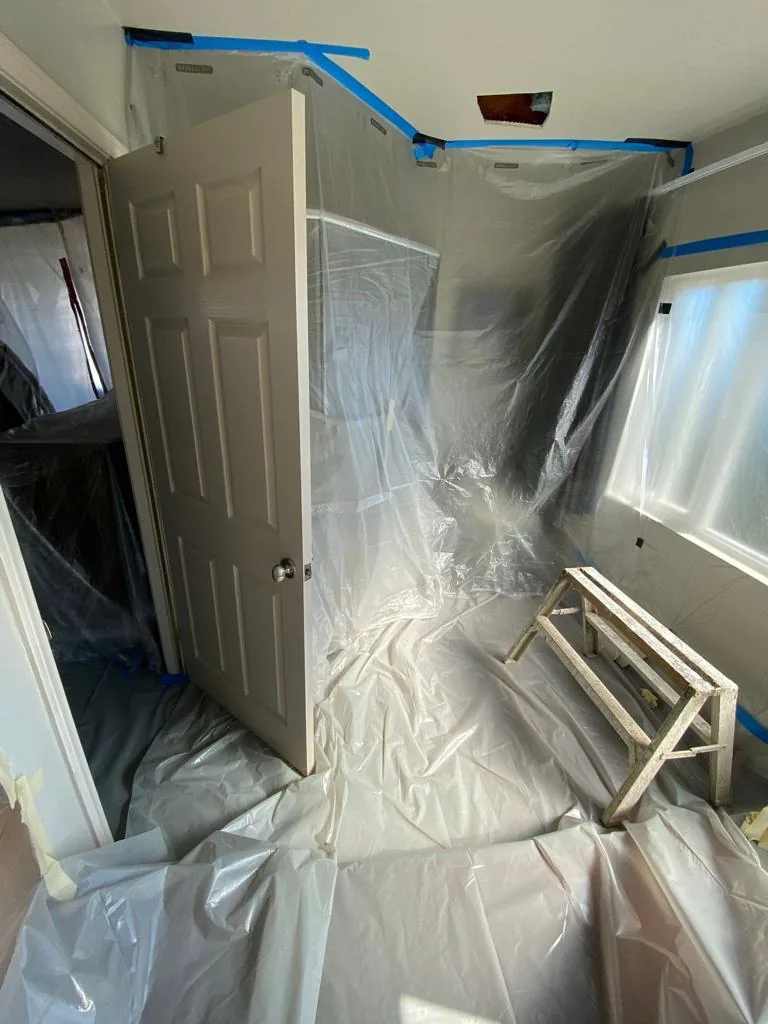 Room sealed floor-to-ceiling with plastic containment sheeting and tape before mold remediation begins.